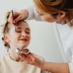 Accueil Makeup artist applying eye shadow to a smiling teen girl. Close up shot highlighting beauty and cosmetics.
