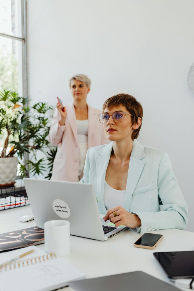 Two professional women collaborate in a modern office, demonstrating teamwork and leadership.